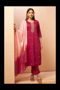 A woman models a traditional Indian salwar kameez suit set in a studio setting. The set includes a deep magenta kurta with gold embroidery on the neckline, matching trousers, and a light pink to magenta gradient striped dupatta.