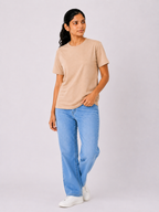 Woman wearing a beige t-shirt and light blue jeans on a white background