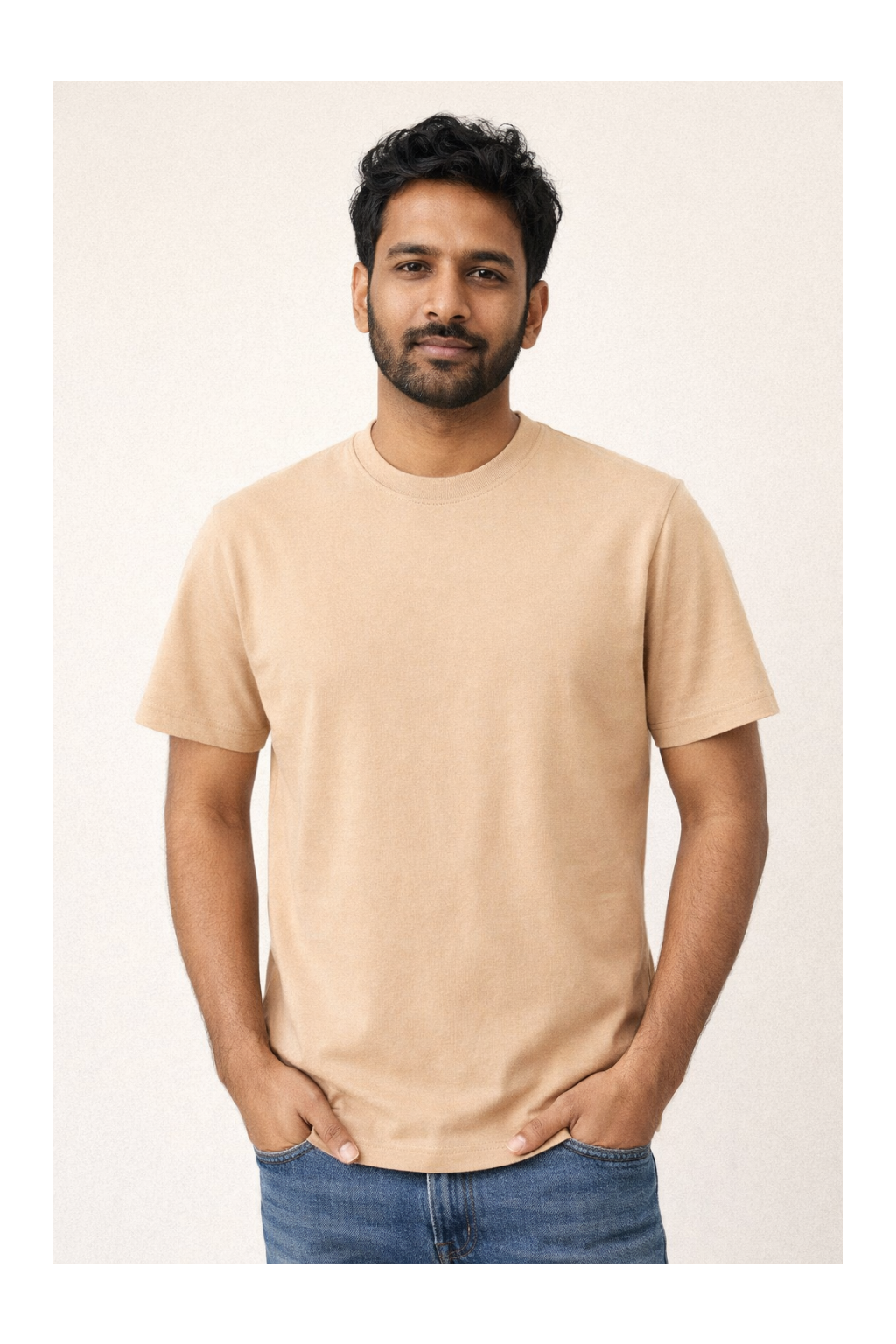 Man wearing a beige t-shirt and blue jeans against a plain background