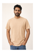 Man wearing a beige t-shirt and blue jeans against a plain background