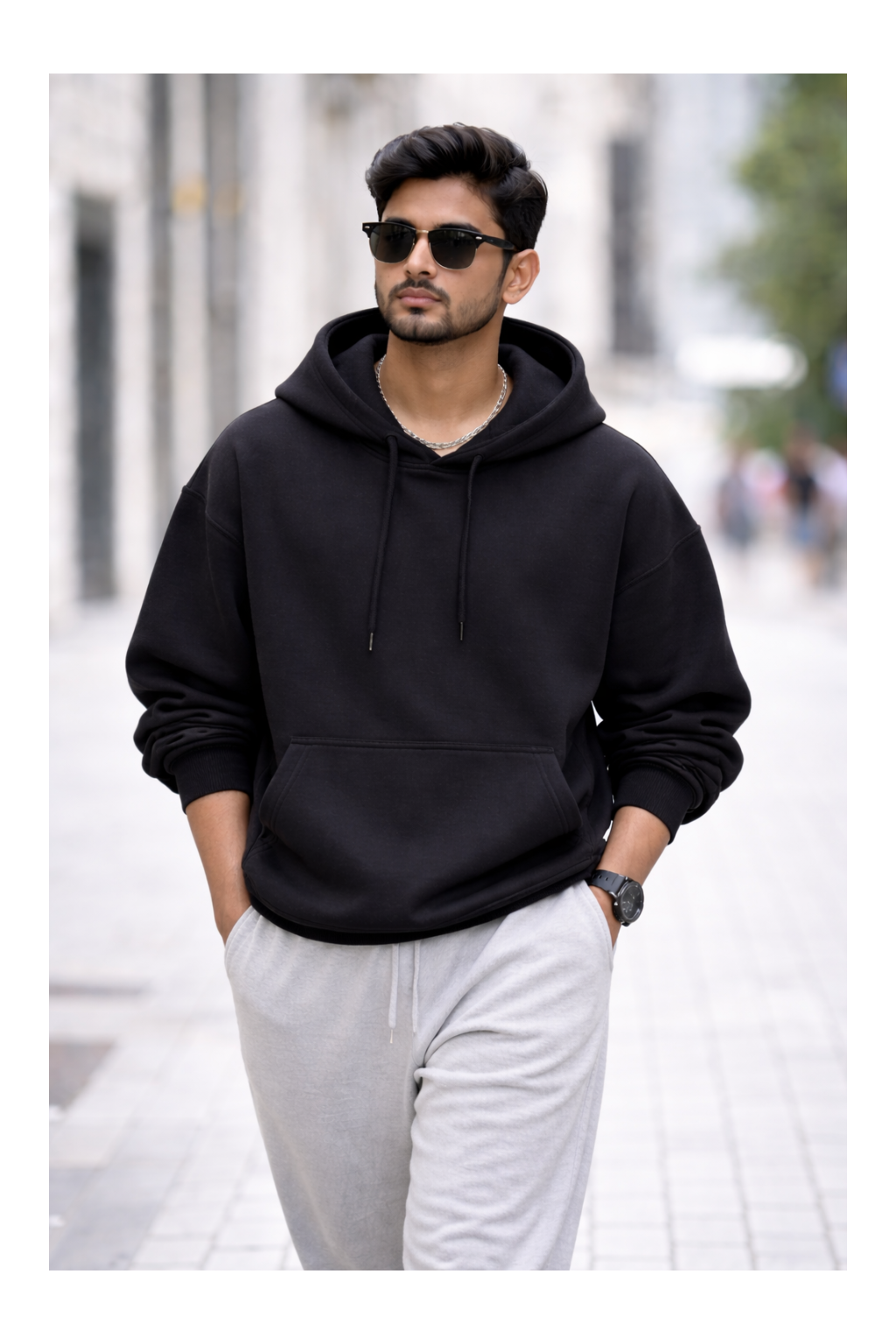 Man wearing a black hoodie and sunglasses on a city street