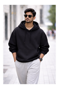 Man wearing a black hoodie and sunglasses on a city street