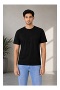 Man wearing a black t-shirt and light blue jeans standing against a neutral background