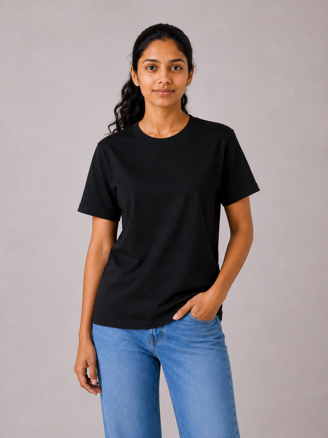 Person wearing a black t-shirt and blue jeans against a gray background