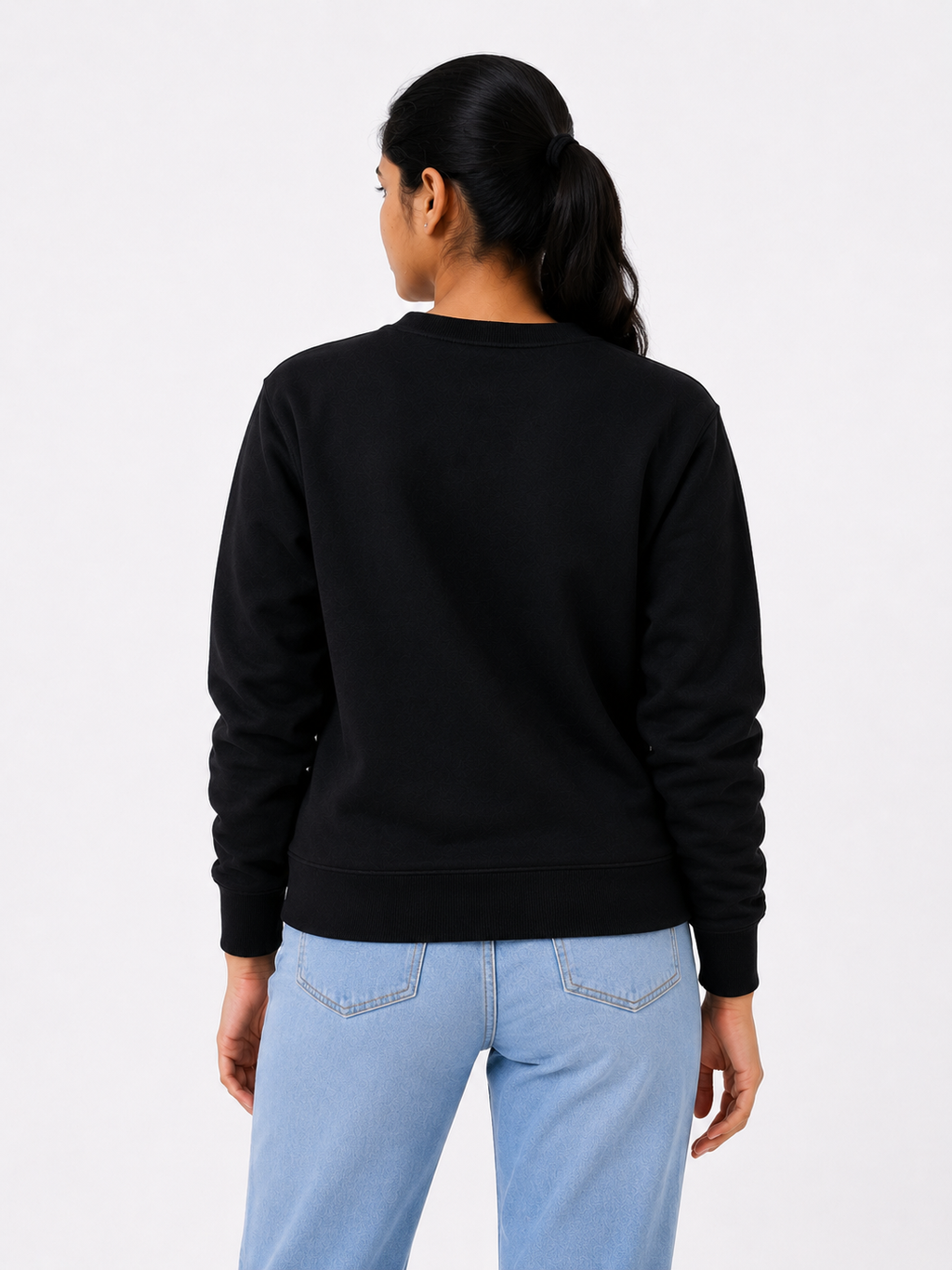 Person wearing a black sweatshirt and light blue jeans on a white background