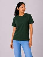 Woman wearing a dark green t-shirt and blue jeans on a gray background
