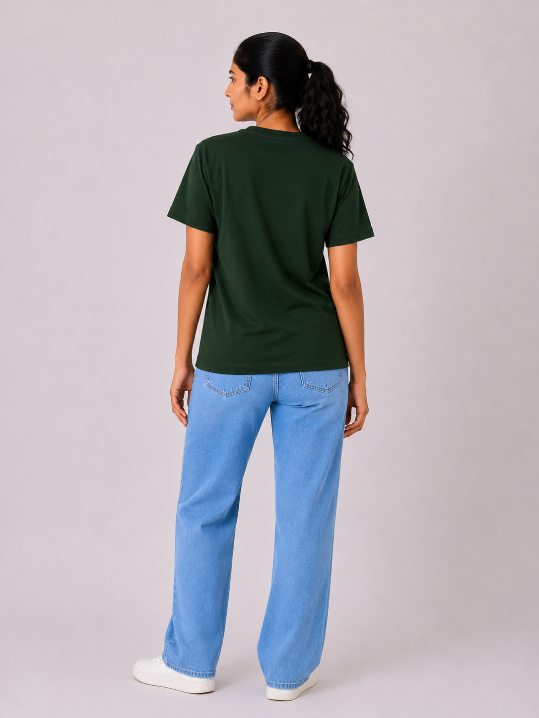 Person wearing a green t-shirt and blue jeans on a plain background