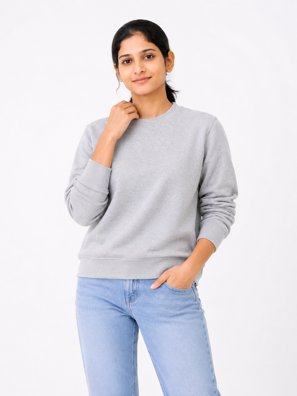 Woman wearing a gray sweatshirt and light blue jeans on a white background