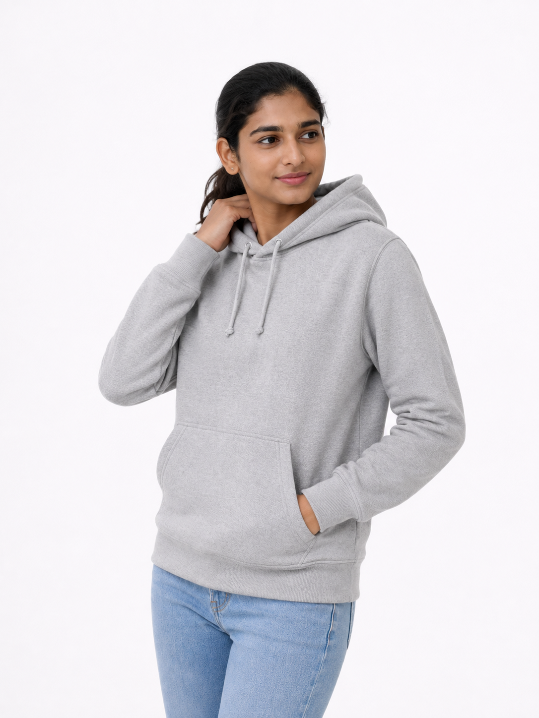 A woman modeling a light gray heather pullover hoodie with drawstrings and a front kangaroo pocket, paired with light blue jeans, against a plain white studio background.