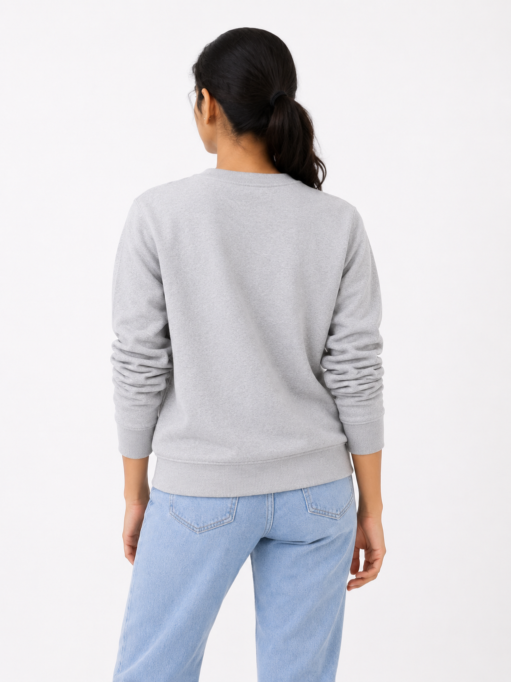 Person wearing a gray sweater and light blue jeans on a white background