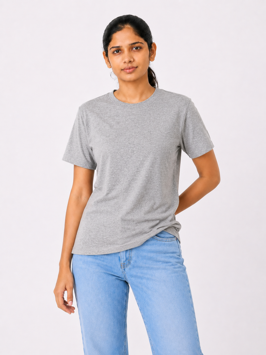 Woman wearing a gray t-shirt and light blue jeans on a white background