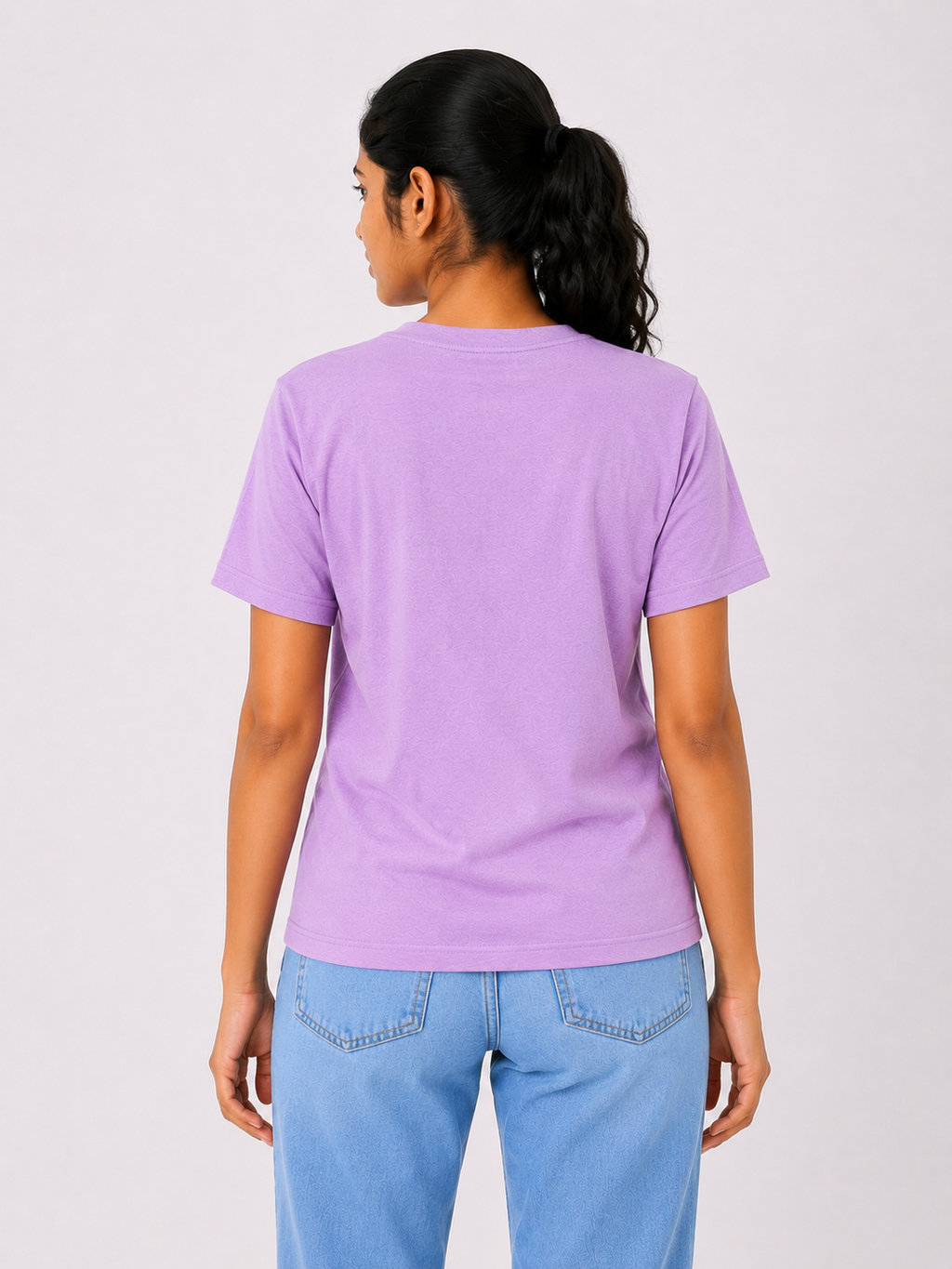 Person wearing a purple t-shirt and blue jeans on a plain background