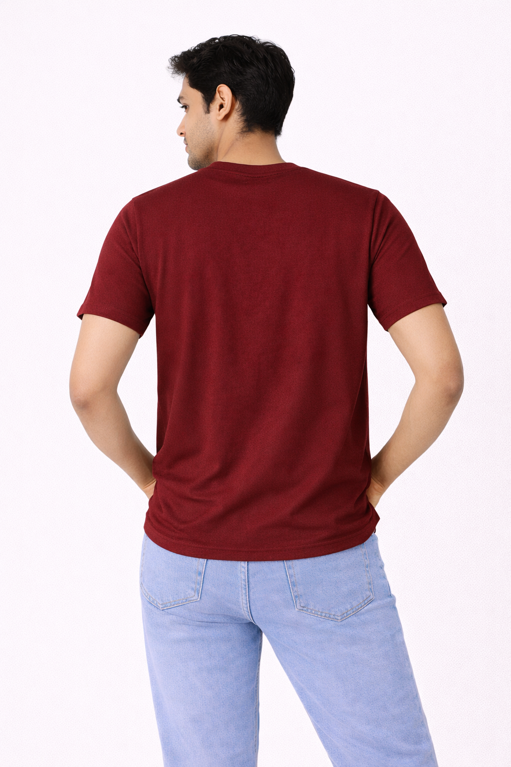 Person wearing a maroon t-shirt and light blue jeans on a white background