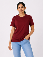 Woman wearing a maroon t-shirt and light blue jeans on a white background