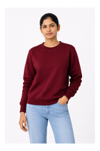 Woman wearing a maroon sweatshirt and light blue jeans on a white background