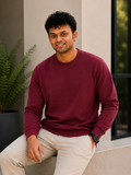 Man wearing a maroon sweater sitting on a step outdoors