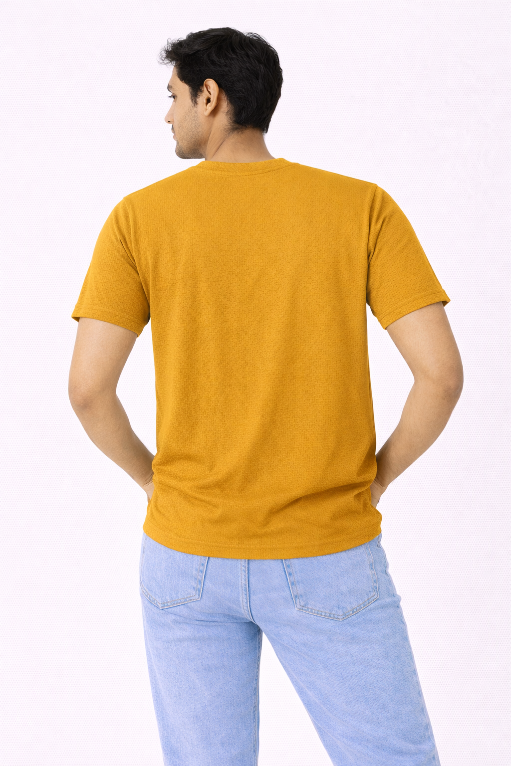 Person wearing a mustard yellow t-shirt and light blue jeans on a white background
