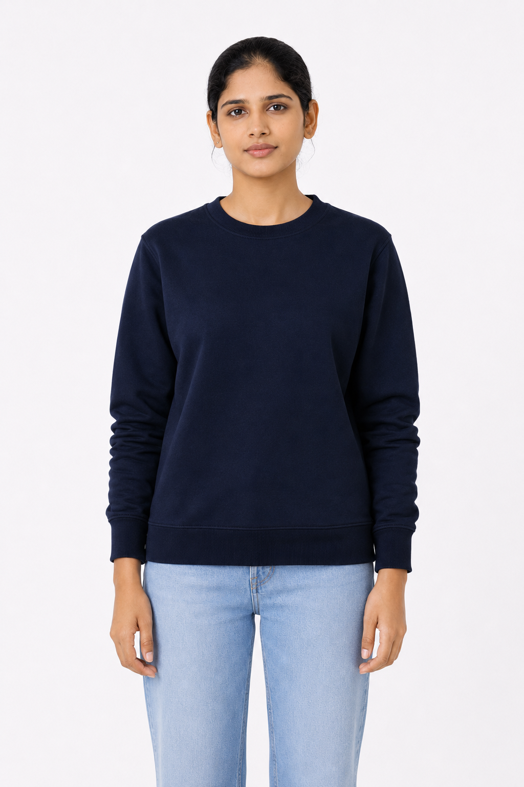 Woman wearing a navy blue sweater and light blue jeans on a white background