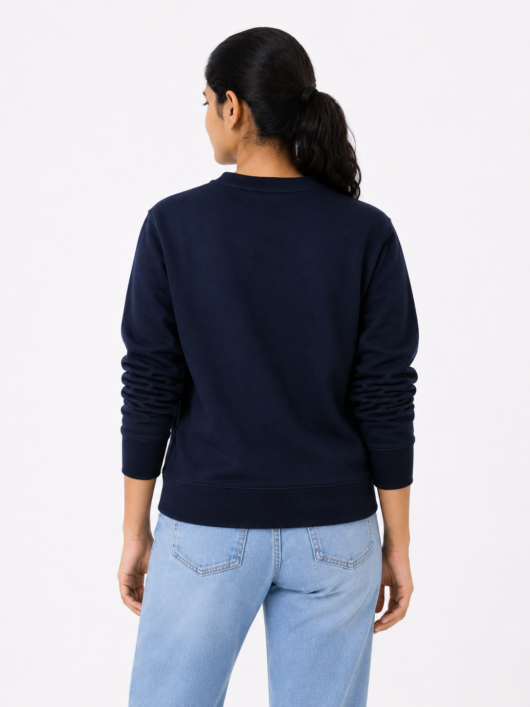 Person wearing a navy blue sweatshirt and light blue jeans on a white background