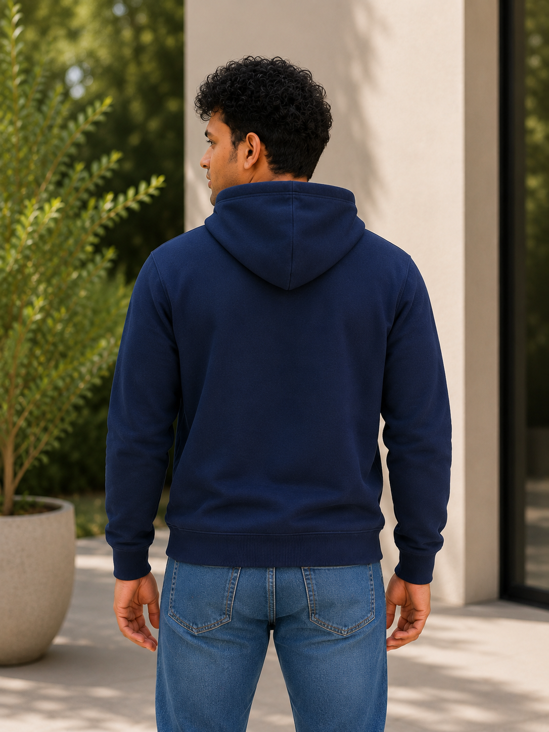 Person wearing a navy blue hoodie and blue jeans standing outdoors.