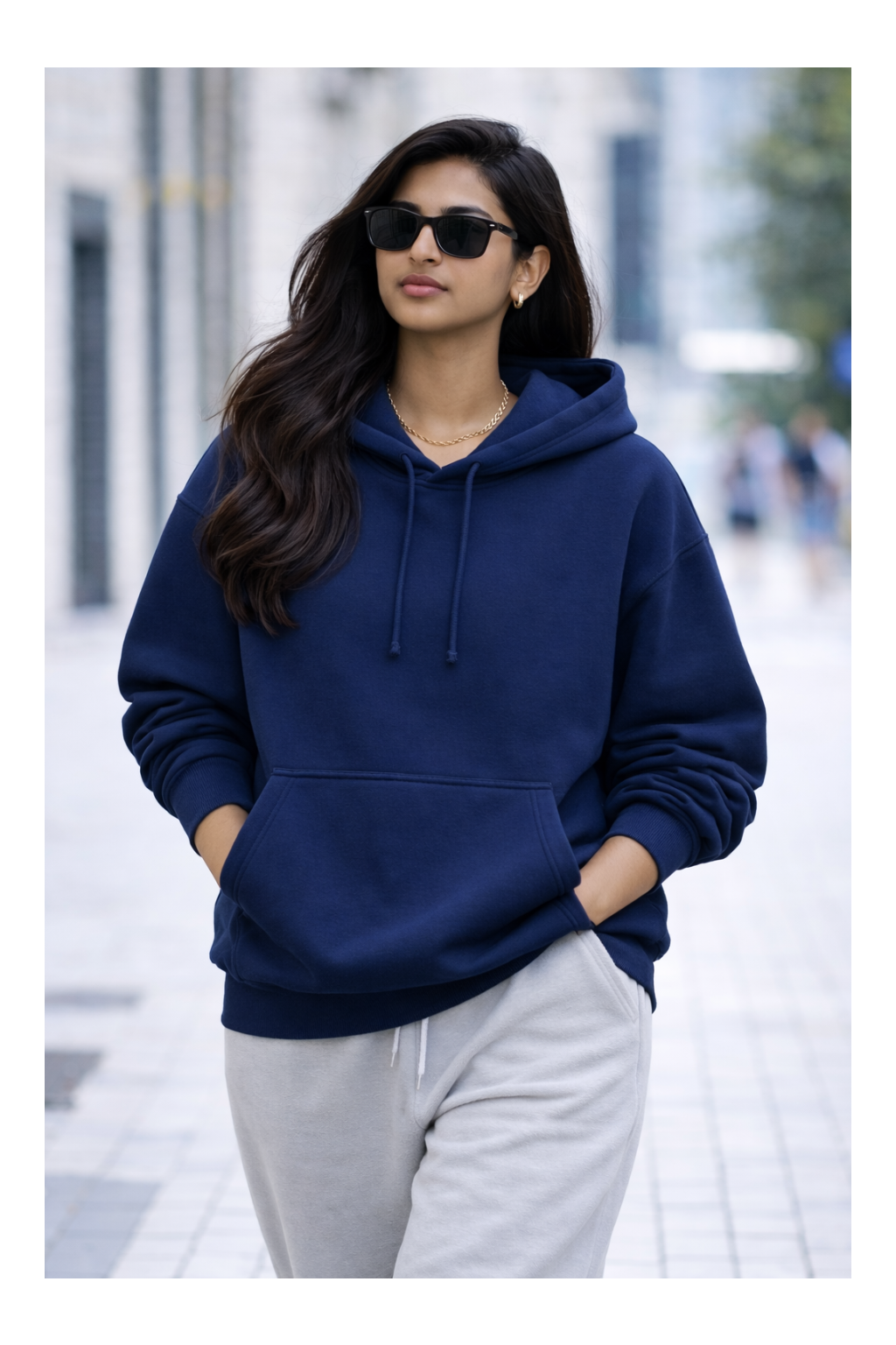 Woman wearing a navy blue hoodie and gray pants on a city street.