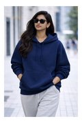 Woman wearing a navy blue hoodie and gray pants on a city street.