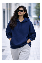 Woman wearing a navy blue hoodie and gray pants on a city street.