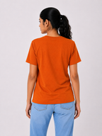 Person wearing an orange t-shirt and blue jeans on a white background