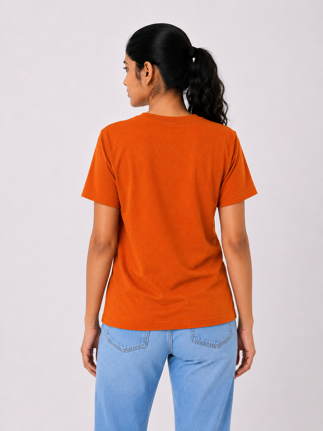 Person wearing an orange t-shirt and blue jeans on a white background