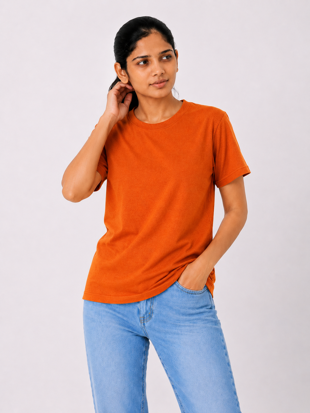 Woman wearing an orange t-shirt and blue jeans on a white background