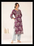 Woman wearing a purple floral patterned kurta with light blue pants on a white background