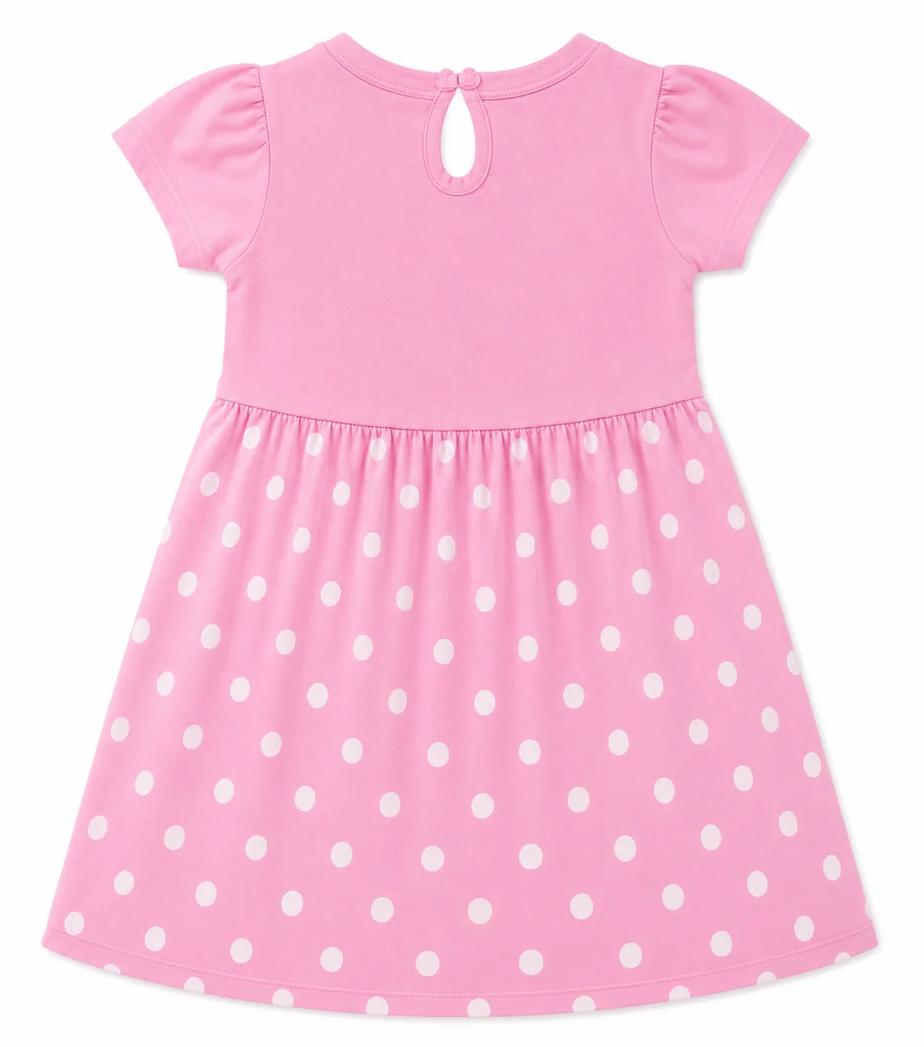 Pink short-sleeve dress with white polka dots on the skirt, featuring a keyhole back neckline with a small button closure, shown against a plain white background.