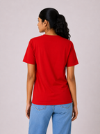 Person wearing a red t-shirt and blue jeans on a plain background