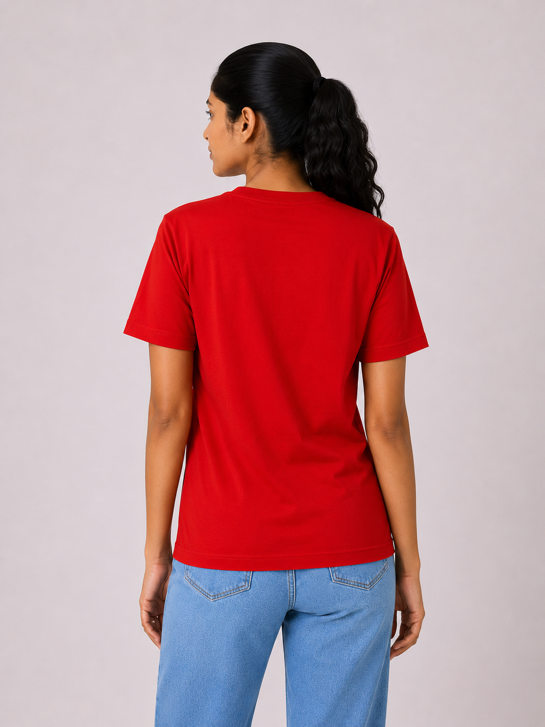 Person wearing a red t-shirt and blue jeans on a plain background