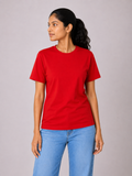 Woman wearing a red t-shirt and blue jeans on a plain background