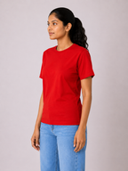 Woman wearing a red t-shirt and blue jeans against a plain background