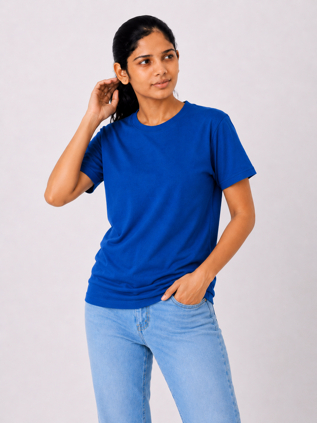 Woman wearing a blue t-shirt and light blue jeans on a plain background