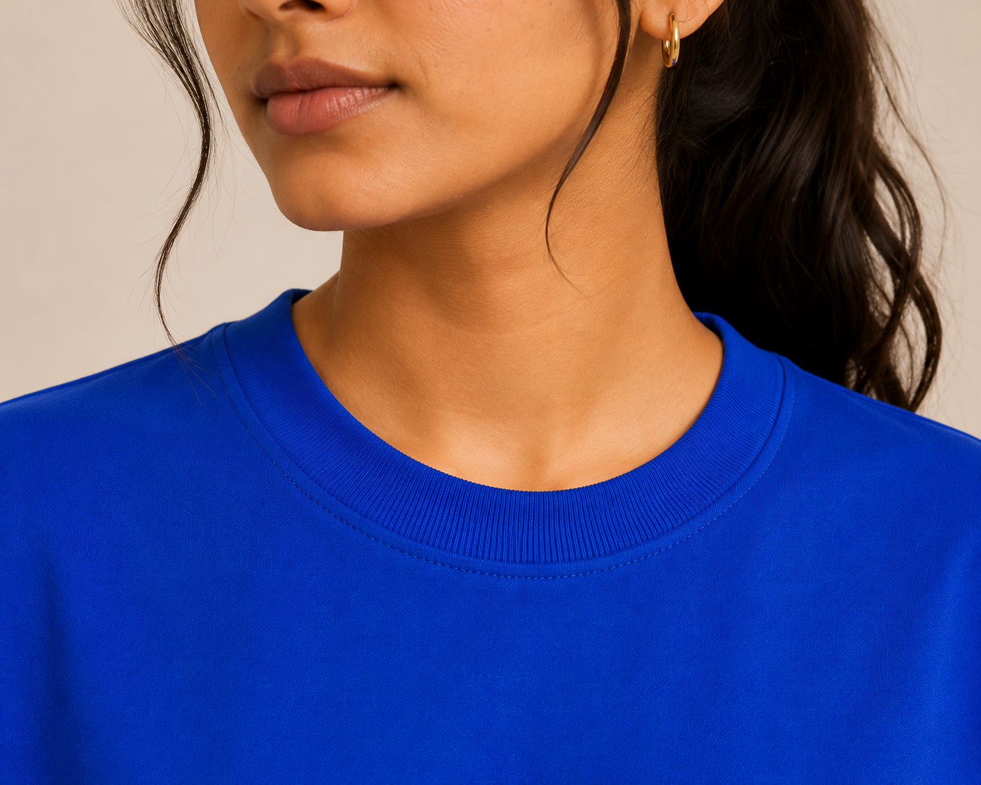 Close-up of a person wearing a blue sweatshirt against a neutral background