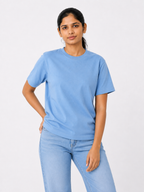 Woman wearing a light blue t-shirt and jeans on a white background