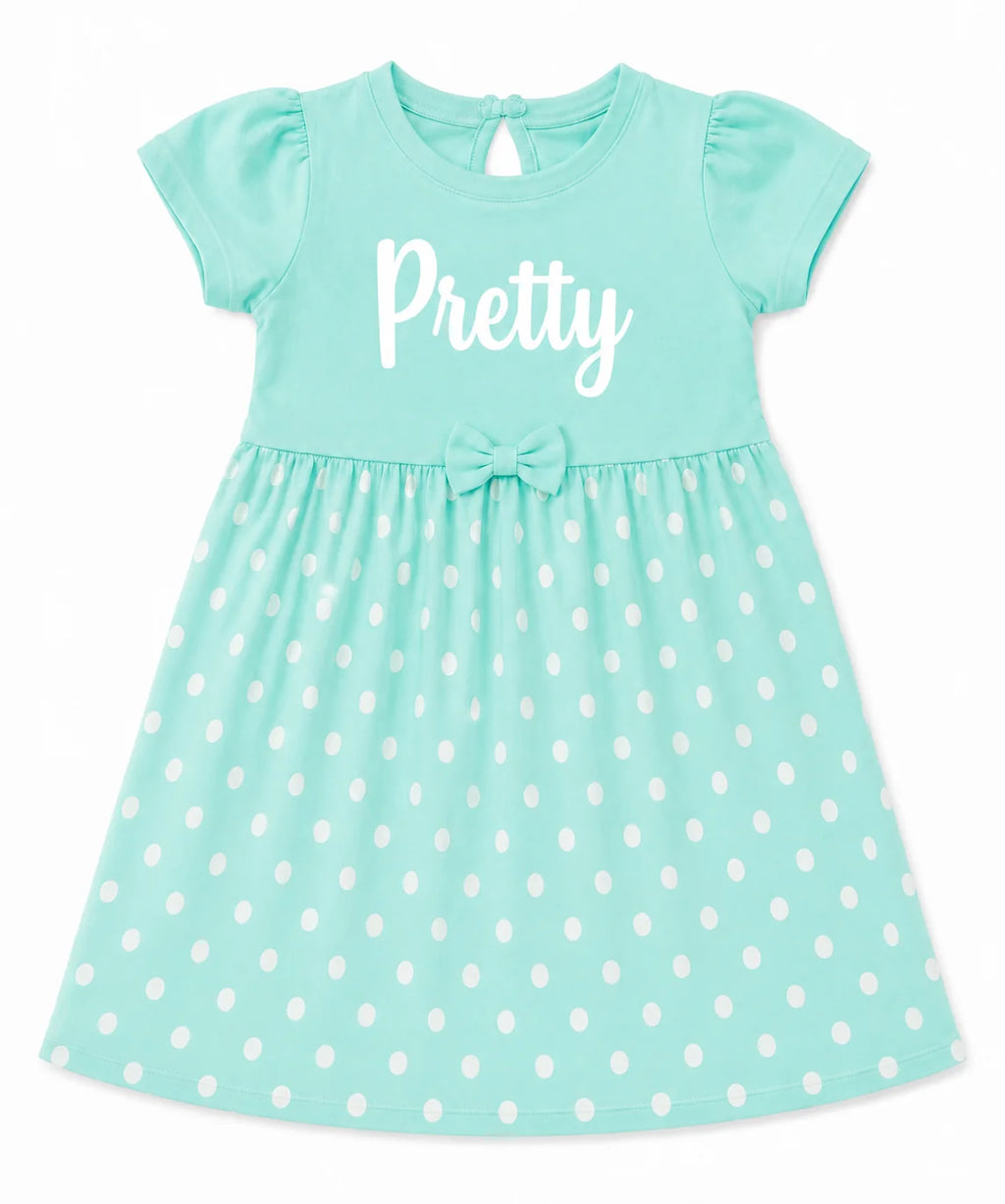 A toddler girl's short-sleeve dress in mint green with white polka dots on the skirt, featuring the word 'Pretty' printed in white script across the chest and a matching bow at the waist.