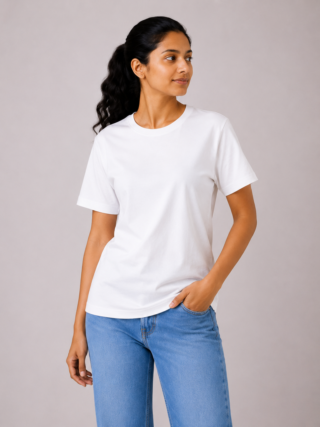 Woman wearing a plain white t-shirt and blue jeans against a neutral background