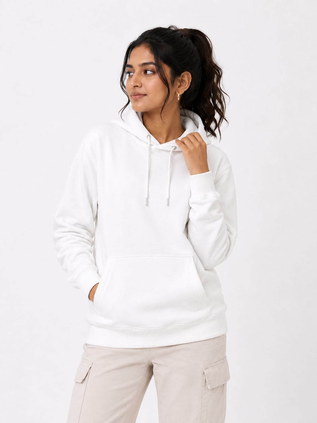 A woman wearing a white pullover hoodie with drawstrings and a kangaroo pocket, paired with light beige cargo pants, photographed against a clean white studio background.