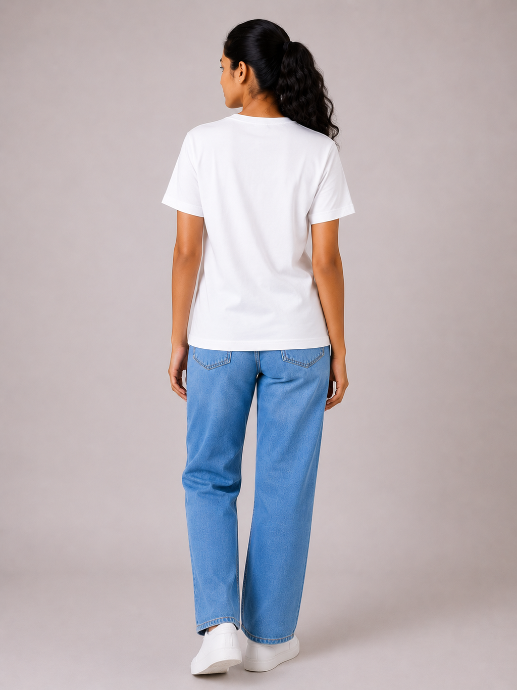 Person wearing a white t-shirt and blue jeans on a plain background