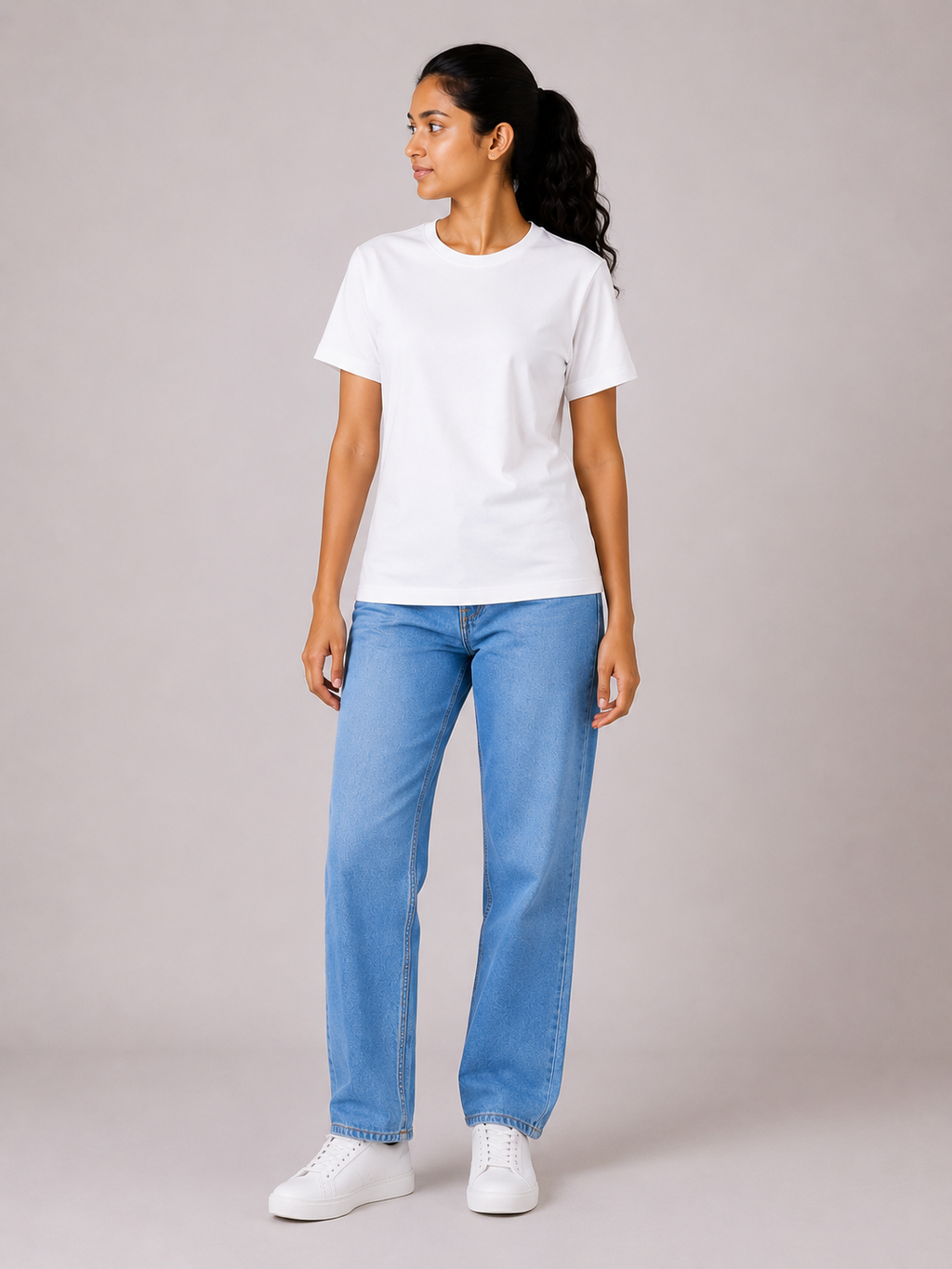 Person wearing a white t-shirt and blue jeans on a plain background