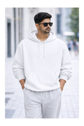 Man wearing a white hoodie and light gray pants on a blurred street background