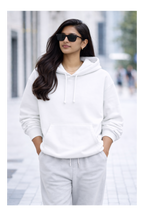 Woman wearing a white hoodie and light gray pants on a blurred street background