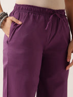 Close-up of a person wearing purple drawstring pants with side pockets, showing the waistband, fabric, and hands at the sides.