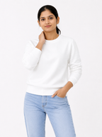 Woman wearing a white sweater and light blue jeans on a white background