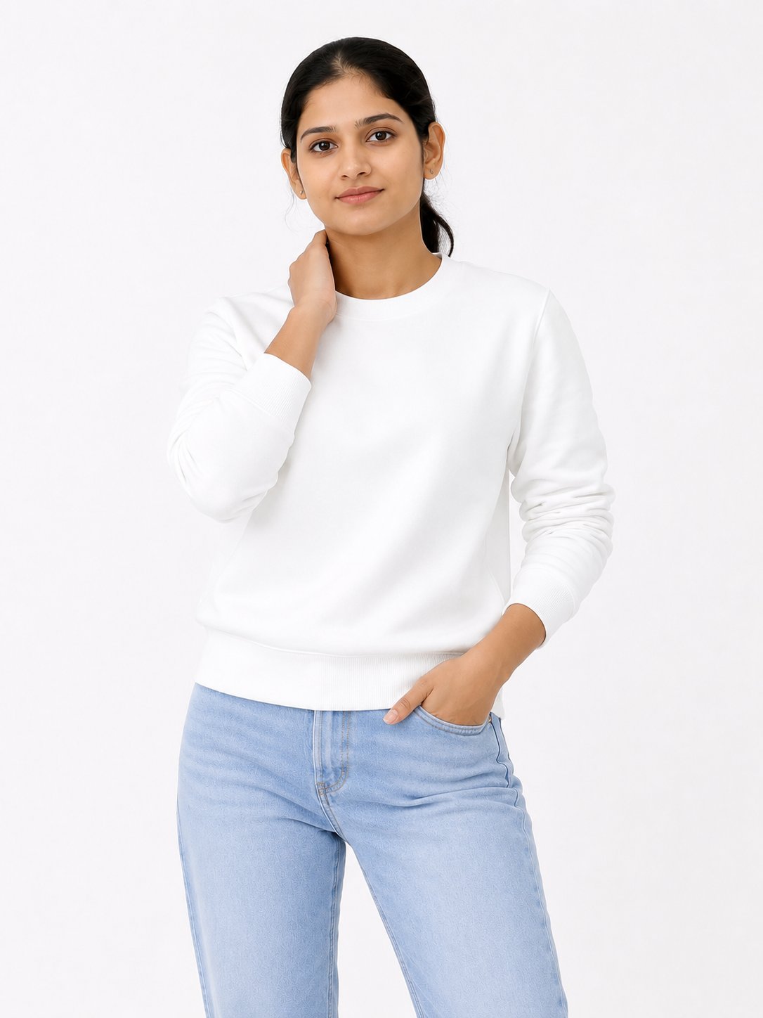 Woman wearing a white sweater and light blue jeans on a white background